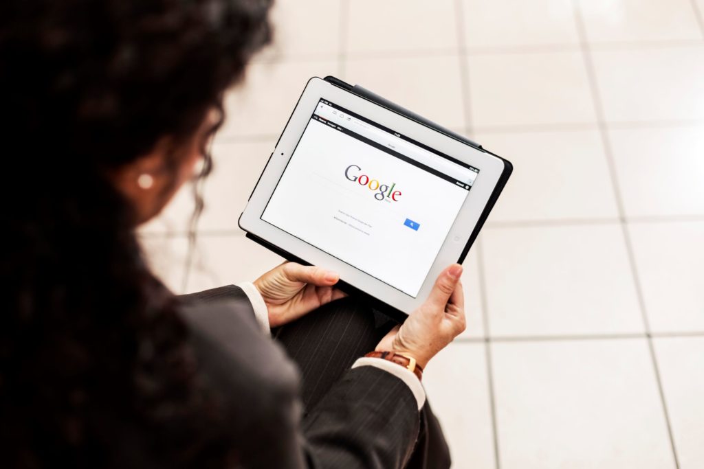 Using Google My Business enhances digital marketing efforts. In this image, a woman is looking at the Google homepage on a tablet.
