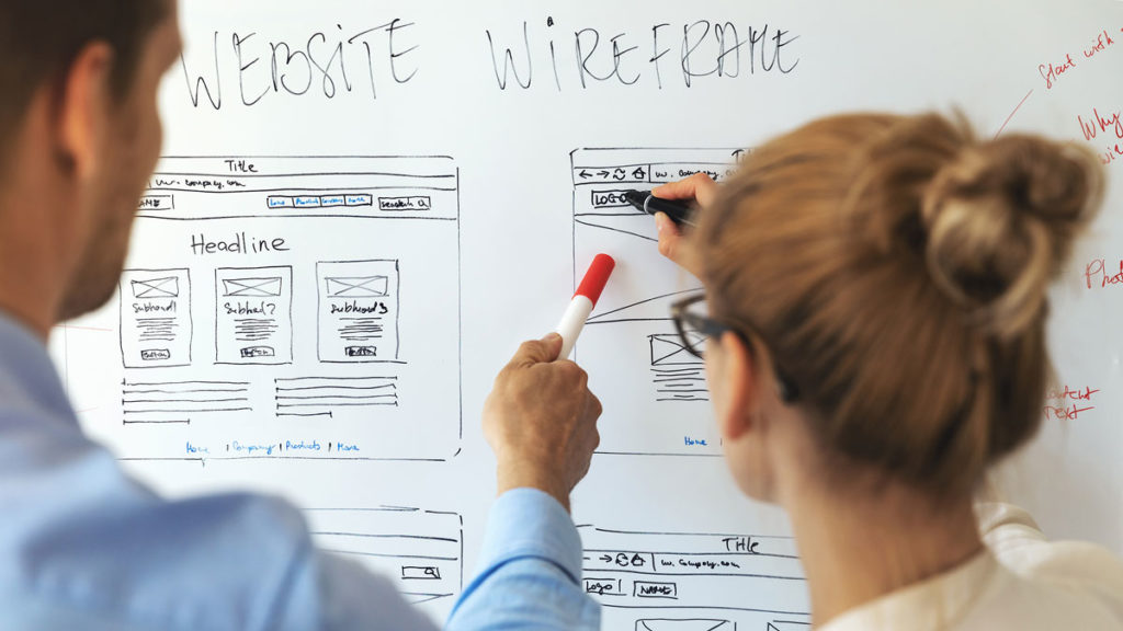 The goal of UI/UX in web design is to create an intuitive, easy-to-use, and enjoyable online experience. In this image, website developers are analyzing wireframes.